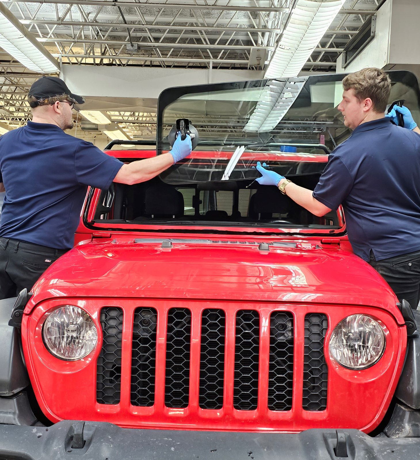Two SGI technicians setting a windshield on a Jeep Wrangler