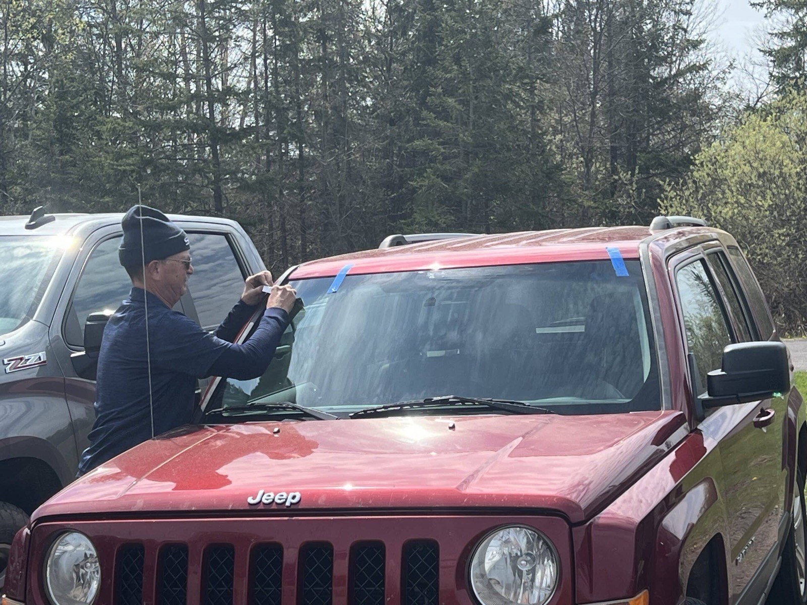 SGI Auto Glass technician setting a windshield on a Jeep at a customer's home